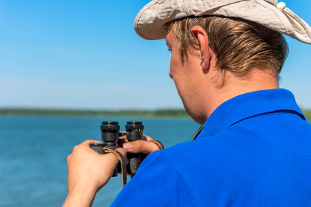 a young man with binoculars on the natureの写真素材
