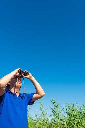man looking through binoculars into the skyの写真素材