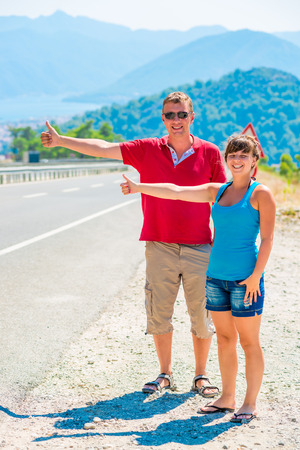 couple of young cheerful tourists hitchhikingの写真素材