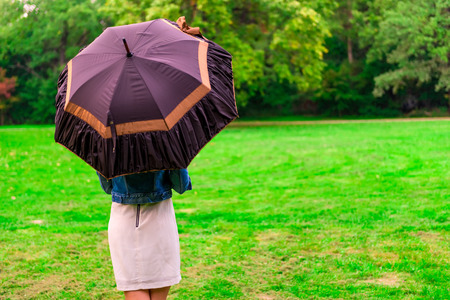 woman standing in the meadow under the open umbrellaの写真素材