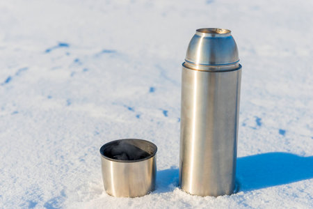 open thermal bottle with boiling water in the snow in the winterの写真素材