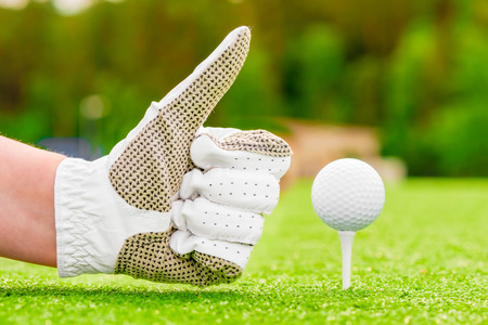 Positive hand gesture near the golf ball on a teeの写真素材