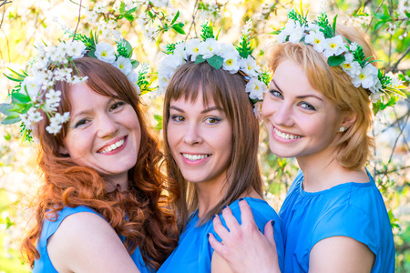 romantic portrait of three women at the time of flowering cherry in the parkの写真素材