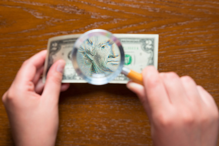 magnifying lens in female hands and two dollarsの写真素材