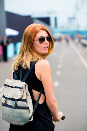 woman rides a scooter in the city with a backpackの写真素材