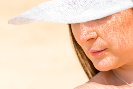 woman's face with the shadow of the white hat close-up