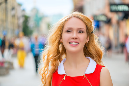 beautiful blonde with curly hair and a smile in the cityの写真素材