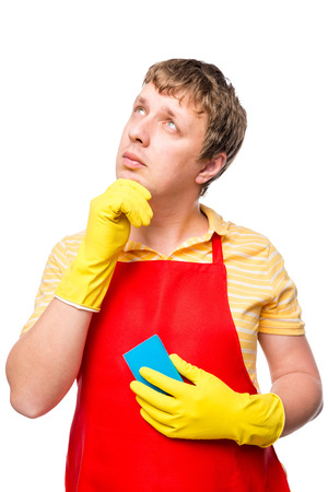 thoughtful male in an apron with a sponge on a white backgroundの写真素材