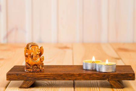 wooden statuette of the god Ganesha and a candle on a supportの写真素材
