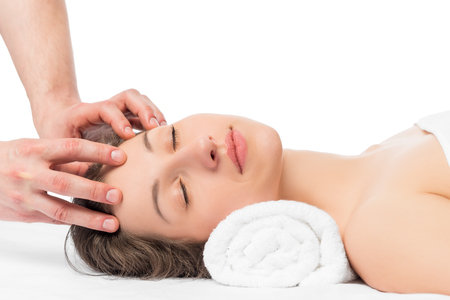 masseur's hands and face of a young girl on a massage tableの写真素材