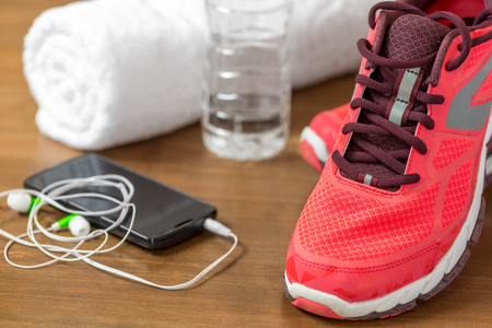 closeup of running shoes and mobile phone headphones on a dark wooden floorの写真素材
