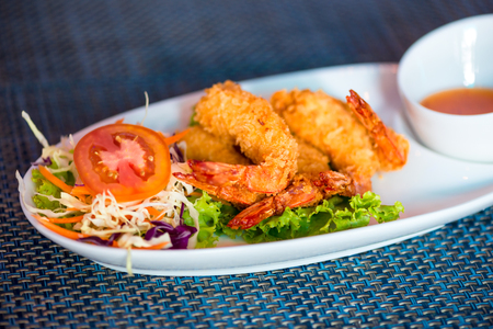 Shrimp in batter with sweet-sour sauce on a close-up plateの写真素材