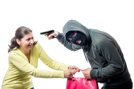 Street thief in a balaclava with a gun steals a woman's bag, shooting on a white backgroundの写真素材