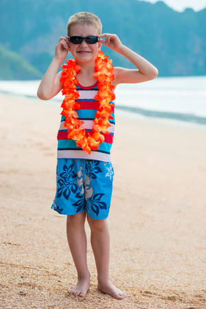 Vertical portrait of a boy in floral lei on a Hawaiian beachの写真素材