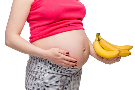 Ripe bananas in the palm of a pregnant woman, photo without a faceの写真素材