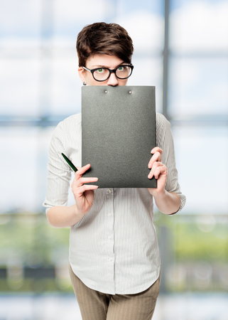 Business woman hiding behind a black folder in the officeの写真素材
