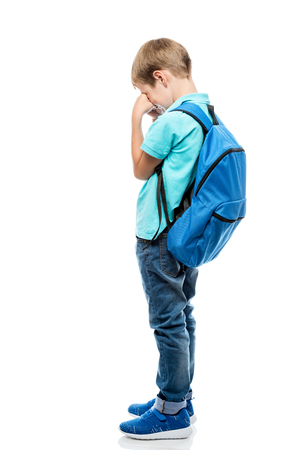 upset schoolboy with backpack crying on white background, isolated in full lengthの写真素材