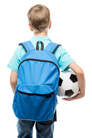 schoolboy with a blue backpack and a football ball back view on a white backgroundの写真素材