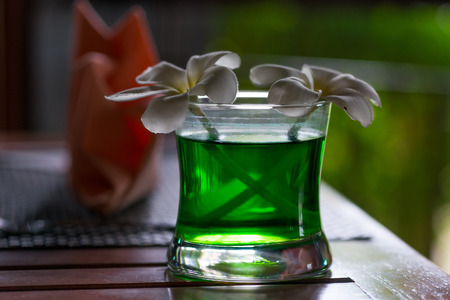 close-up of a glass with tropical plumeria flowers on a table in a cafeの写真素材