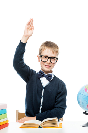 vertical portrait of a schoolboy wearing glasses at a table in a studioの写真素材