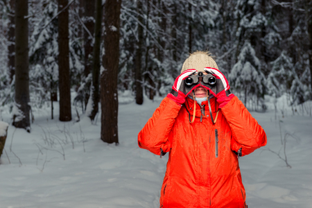 woman tourist with binoculars in the winter forestの写真素材