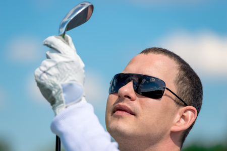 portrait of a golfer looking at his golf club close upの写真素材