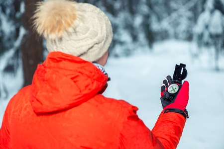 the girl is guided in the winter forest by the compass, the view from the backの写真素材