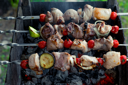 tasty shish kebab with vegetables on skewers on barbecue over coalsの写真素材