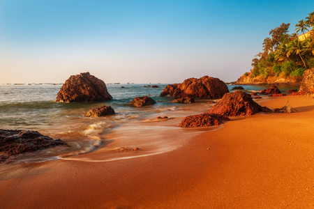 sandy beach and large boulders in the sea water. Tinted in red.の写真素材