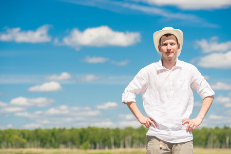 horizontal portrait of a man in a hat and white shirt in the fresh air against the skyの写真素材