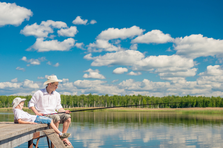 relaxed boy with his father on a fishing trip on a beautiful lakeの写真素材