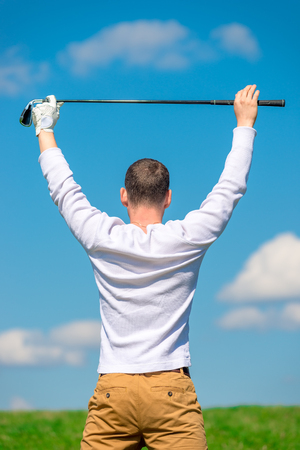 professional golfer rejoices in victory with a raised golf club over his head in the fieldの写真素材