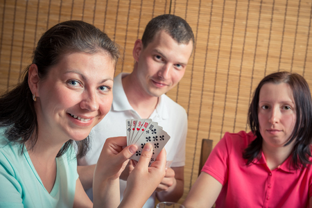 happy man and two women playing poker, a woman showing their cardsの写真素材