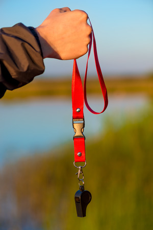 close-up of a whistle on a lace in a male hand in the fresh airの写真素材