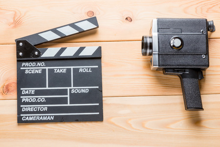 Video Clapper and Vintage Camcorder Lies on Light Wooden Boardsの写真素材