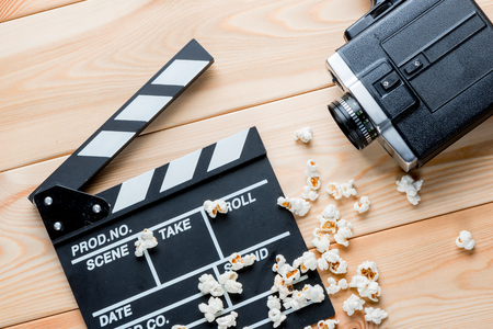 video clapper, retro video camera and salted popcorn top view on wooden boardsの写真素材