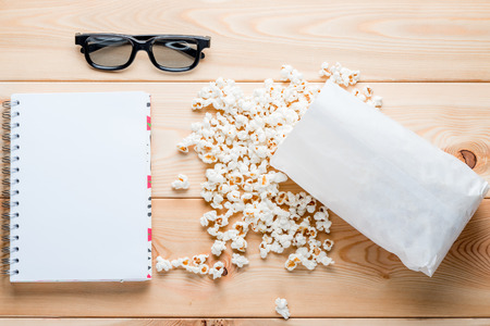 Notepad for entries, 3d glasses and salty popcorn on wooden boardsの写真素材