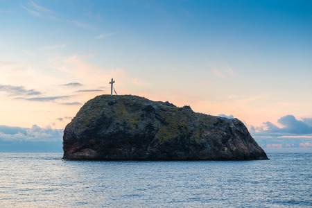 Rock with a cross on top and the sea, the dawnの写真素材