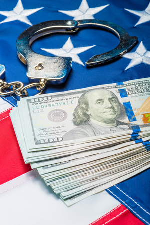 heap of money and handcuffs on american flag close up concept photoの写真素材