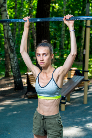 beautiful sporty woman on the sports field with a horizontal bar, outdoor exerciseの写真素材