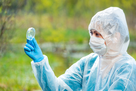 a researcher with a flask and samples of plants from a forest river is studyingの写真素材