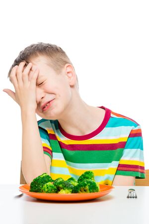sad boy does not want to eat broccoli, a portrait with a plate on a white backgroundの写真素材