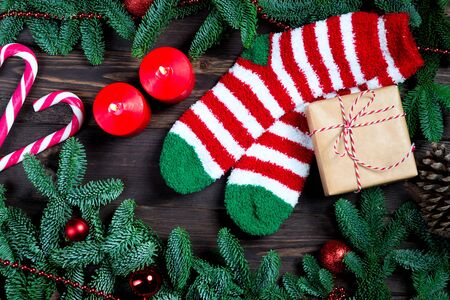 Warm striped socks, a gift in craft paper, branches of fluffy spruce on a dark wooden tableの写真素材