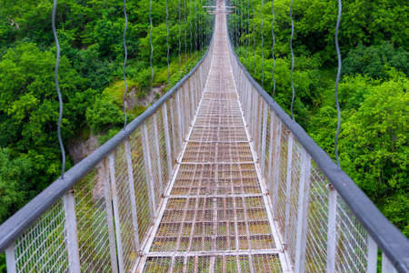Swinging suspension bridge leading to the cave city of Khndzoresk over a gorge in the mountains of Armeniaの写真素材