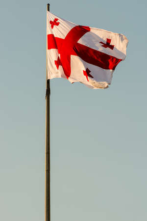 Georgia flag waving on a flagpole against sky backgroundの写真素材
