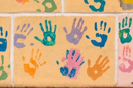 Multicolored painted hand prints on a yellow wallの写真素材