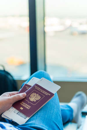 Closeup of female holding passports and boarding pass at airportの写真素材