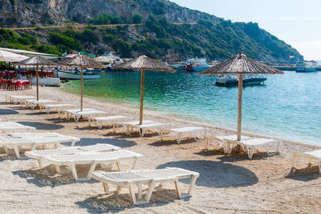 Summer vacation destination. Straw sunshades and sunbeds on the empty beach with sea in the background.の写真素材