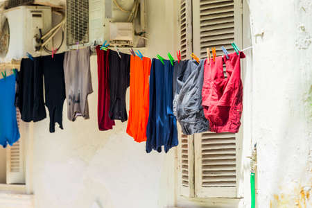 Clean, washed clothes are dried on a rope with clothespins in the outdoorsの写真素材