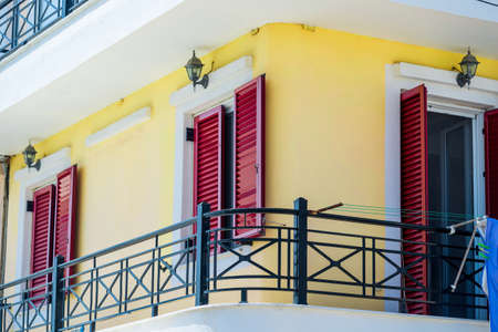Old mediterranean red window shutters and building backgroundの写真素材